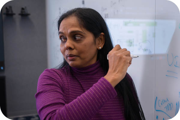 Tech associate writing on a whiteboard in a meeting